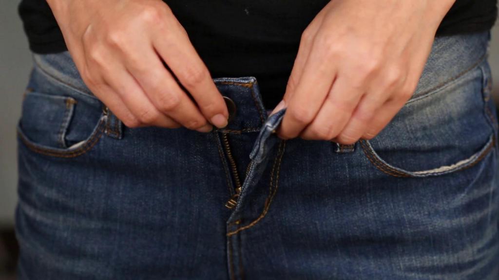 Женщина застегивает джинсы